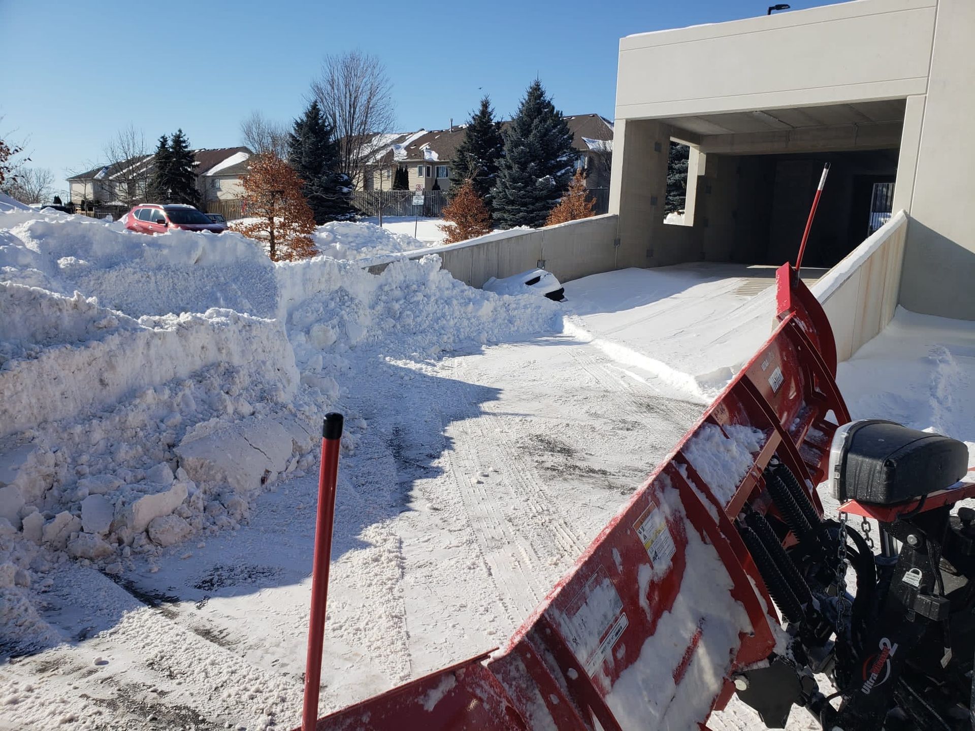 A snow plow is being used to remove snow from a driveway