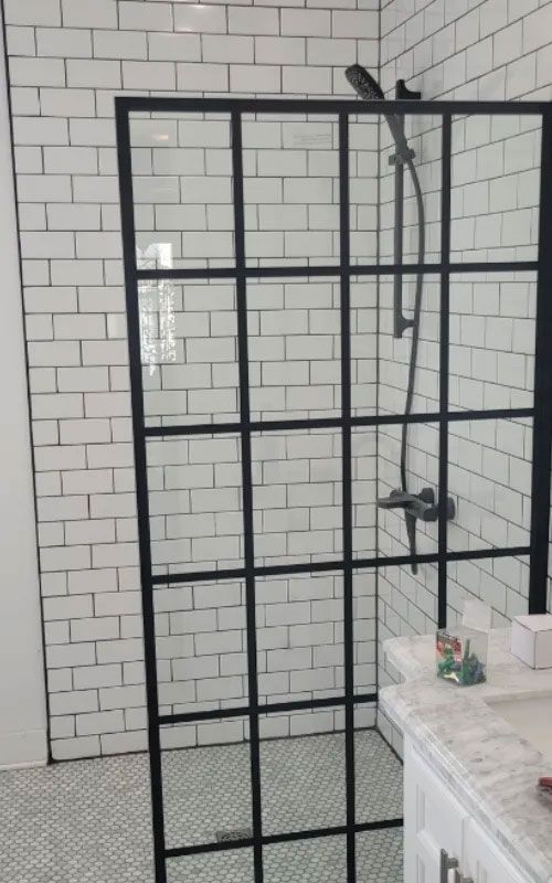 Une salle de bain avec carrelage métro blanc et une douche à l'italienne avec un cadre noir.