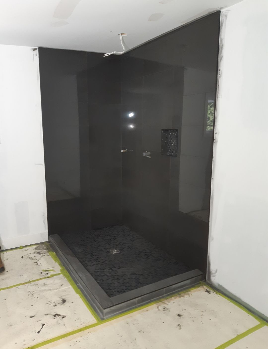 Une salle de bain avec une douche à l'italienne noire et un mur blanc.