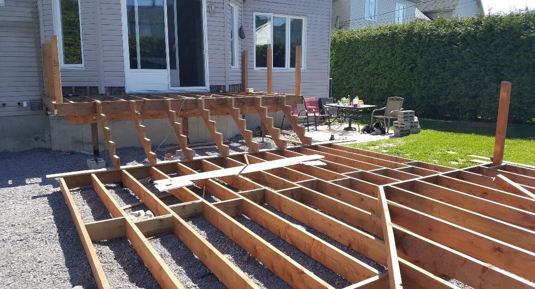 Une terrasse en bois est en cours de construction devant une maison.