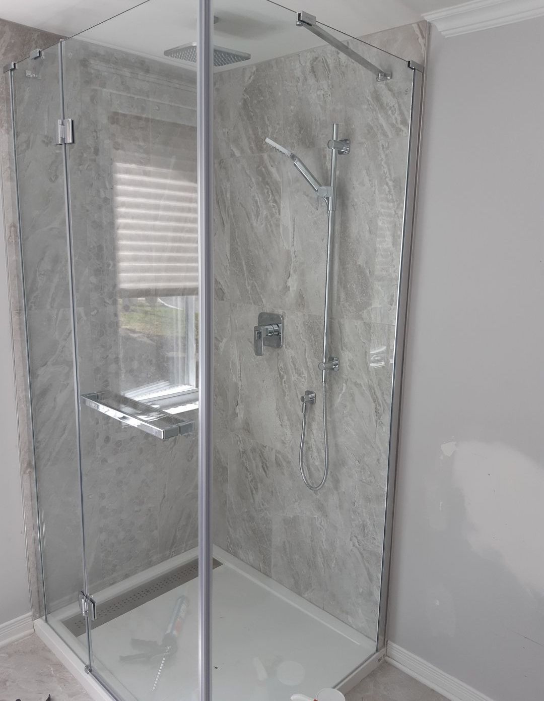 Une salle de bain avec douche à l'italienne et fenêtre.