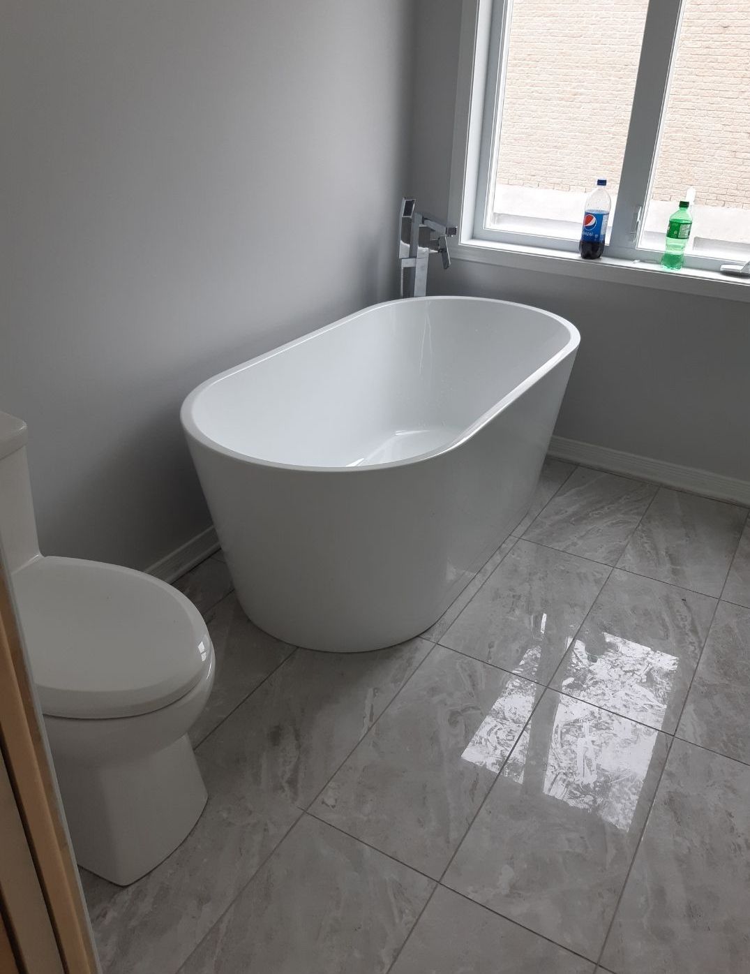 Une salle de bain avec WC, baignoire et fenêtre.