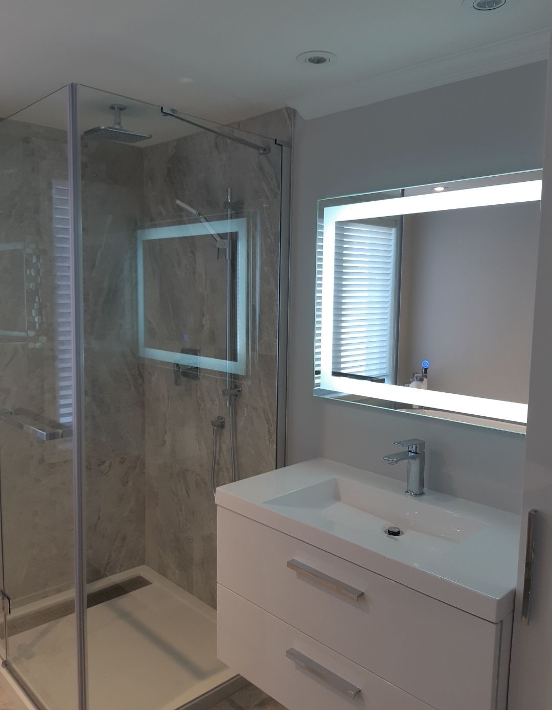 Une salle de bain avec lavabo, miroir et douche à l'italienne.