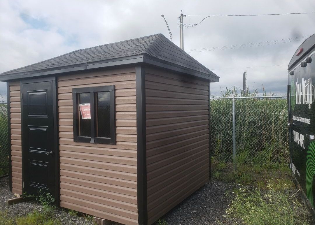 Un petit hangar en bois se trouve au milieu d'un champ herbeux.