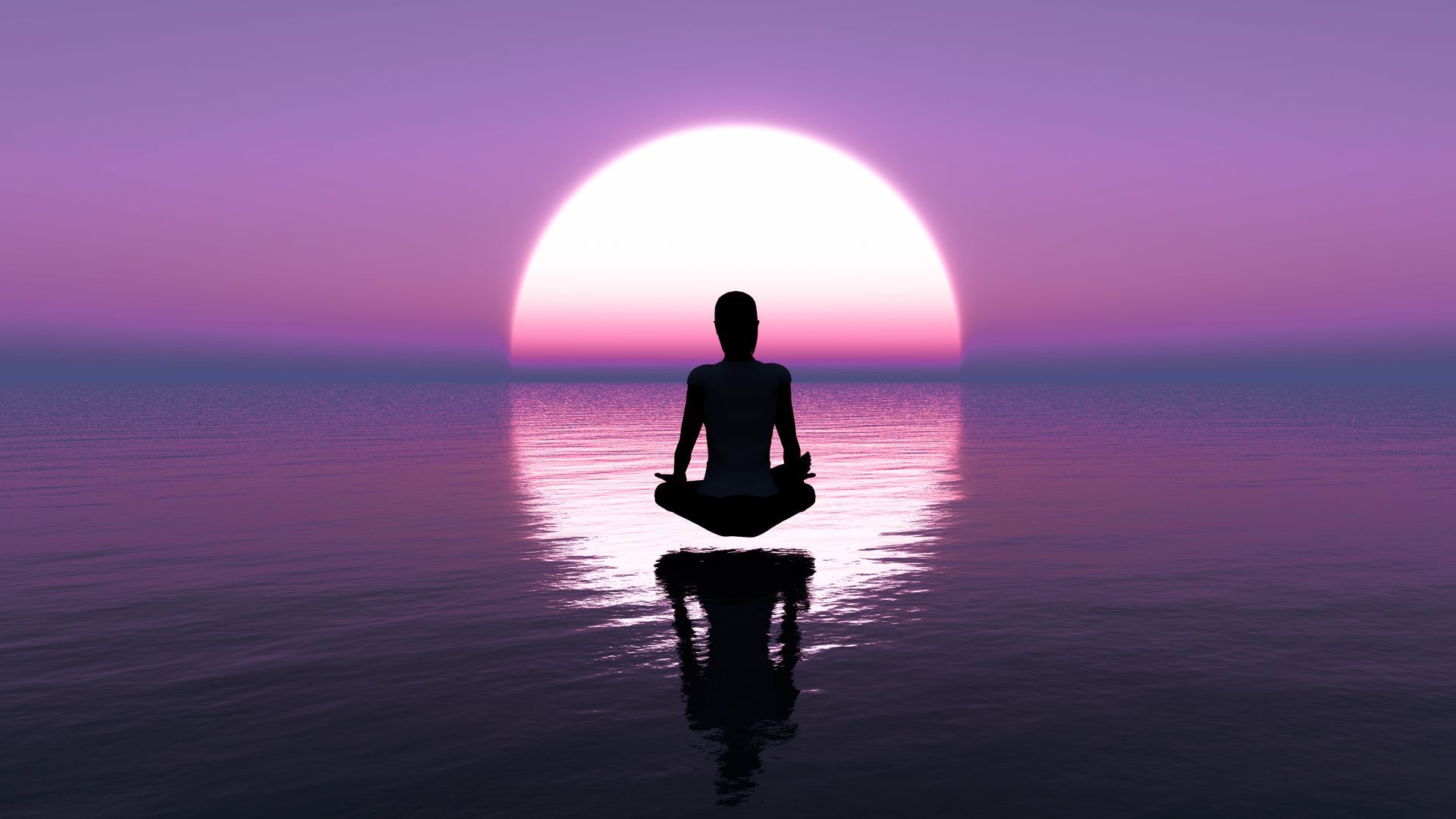 A person is meditating in the ocean at sunset.