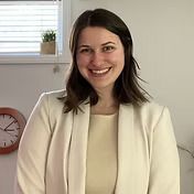 Woman with shoulder-length brown hair, smiling, wearing a cream blazer and dress.