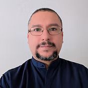 Man with glasses and goatee, wearing a dark blue shirt, looking at the camera.