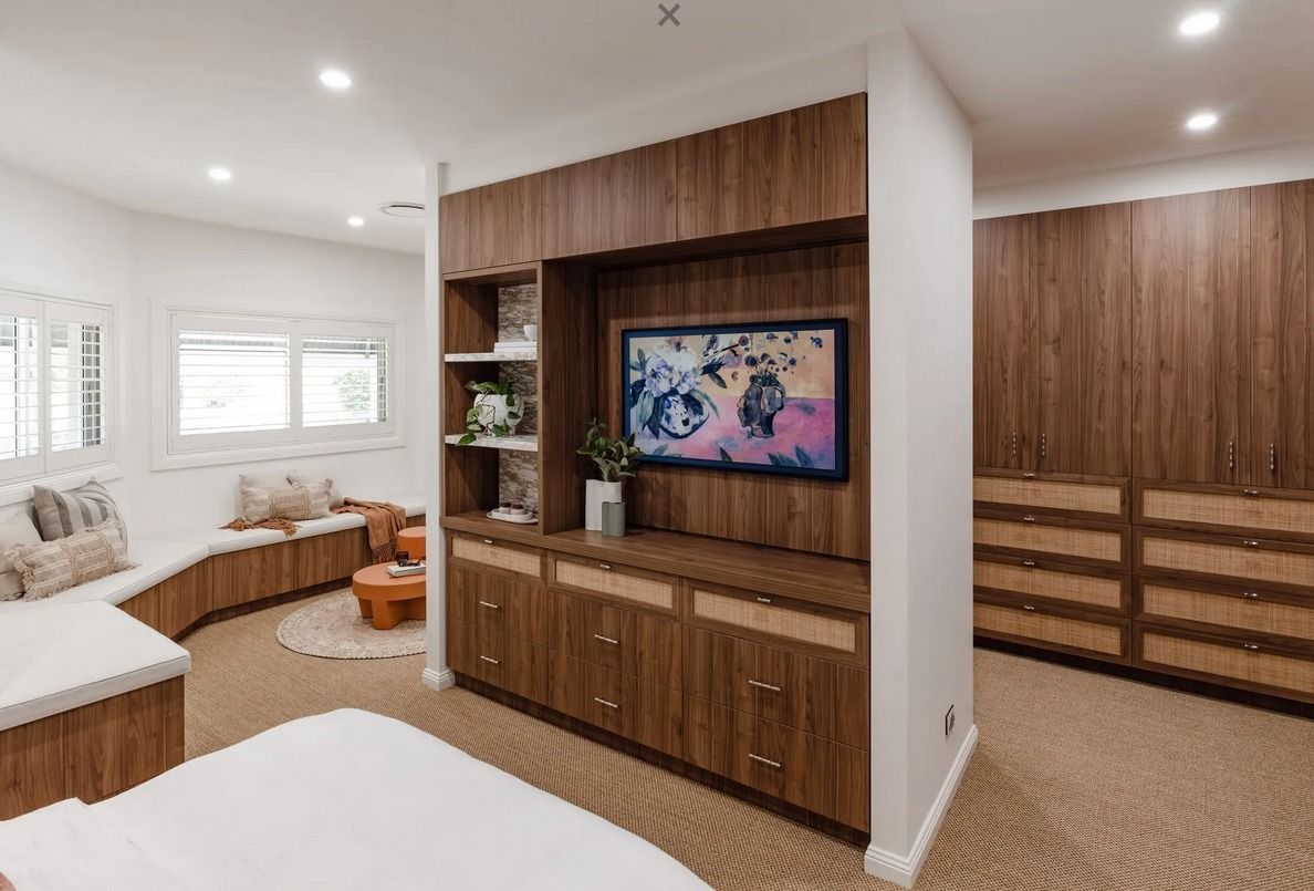 A room features a central wood partition with an integrated TV and shelving, separating a seating area from a closet. — PKJ Design in Unanderra, NSW 