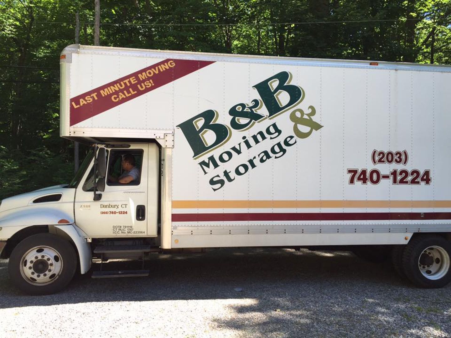 A b & b moving and storage truck is parked in a gravel lot