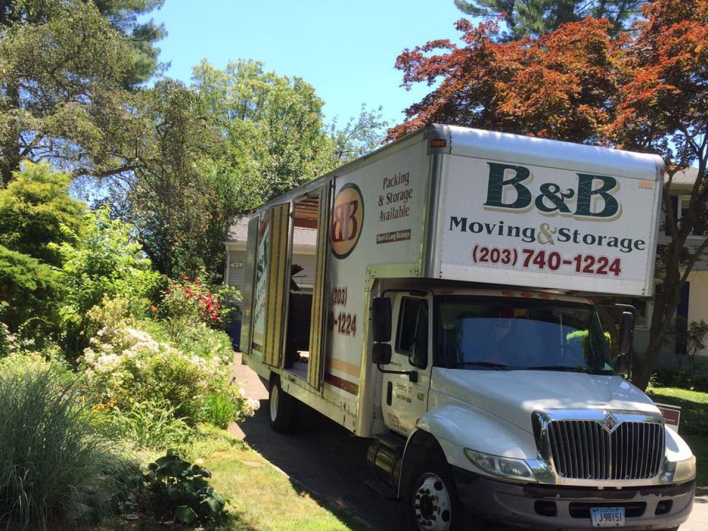 A moving and storage truck is parked in front of a house.