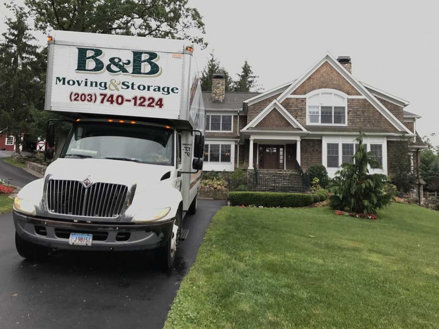 A b & b moving and storage truck is parked in front of a house