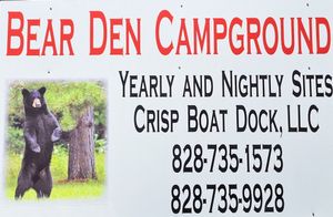 A sign for bear den campground with a picture of a bear