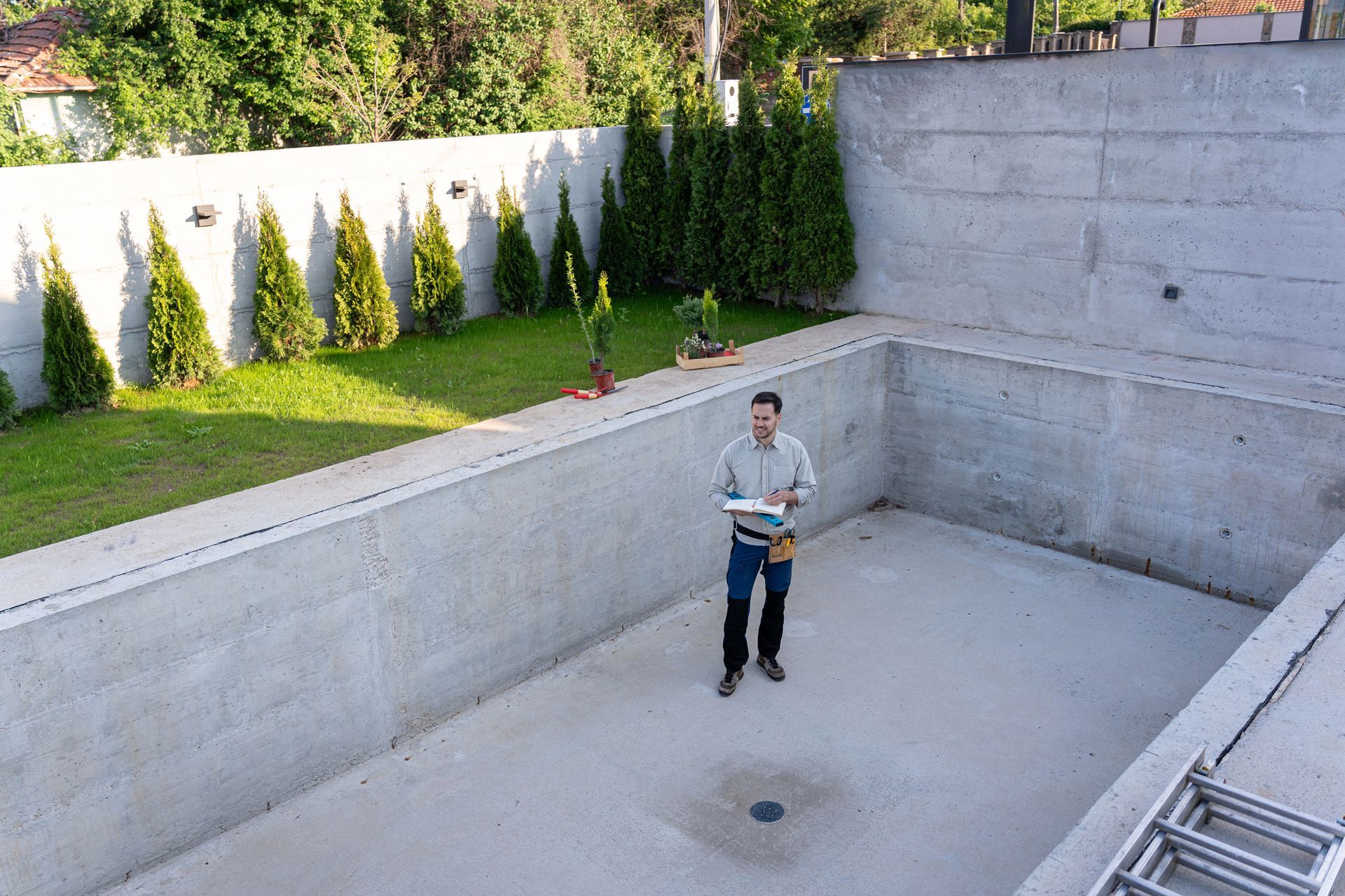 A male professional engineer inspecting a new swimming pool construction.