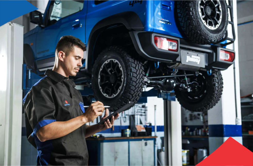 Um homem está trabalhando em um jipe azul em um elevador em uma garagem.