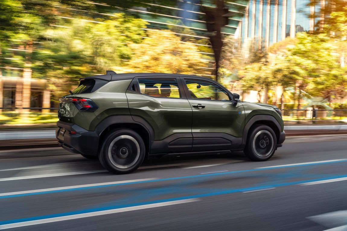 Um homem está trabalhando em um jipe ​​azul em um elevador em uma garagem.