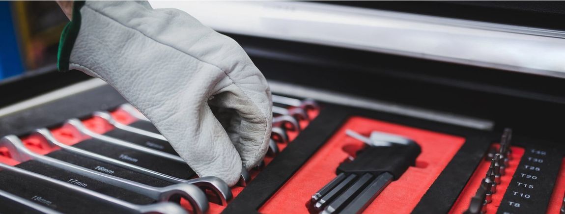 Um homem está trabalhando em um jipe ​​azul em um elevador em uma garagem.