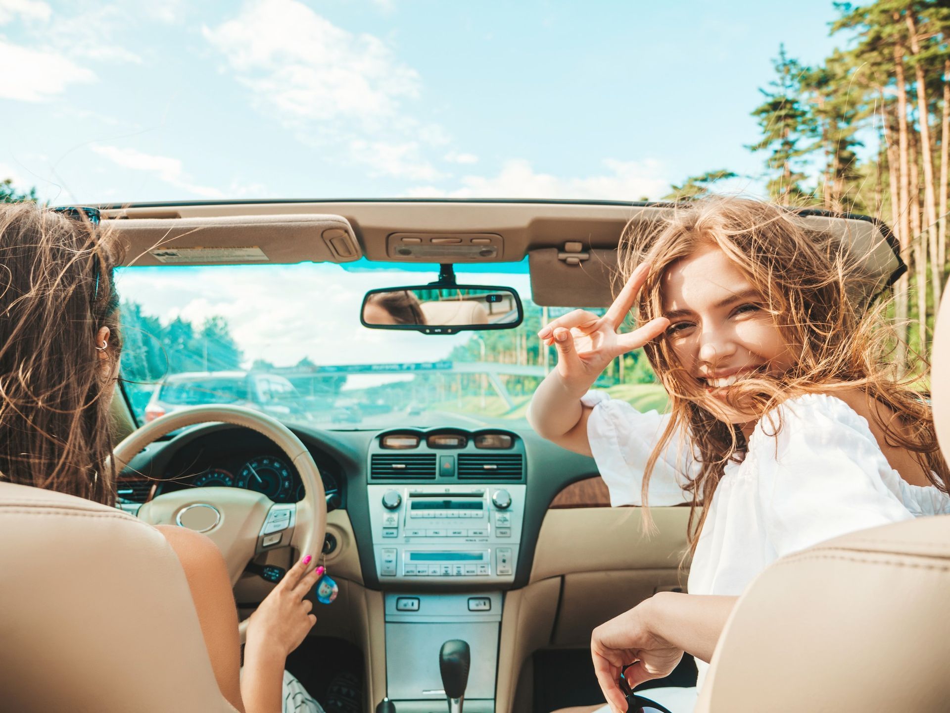 Two women are sitting in a convertible car.