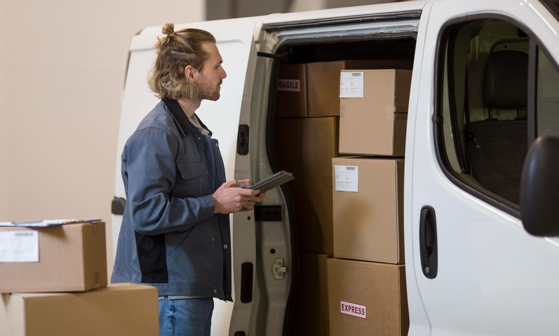 A man is standing next to a white van filled with boxes.