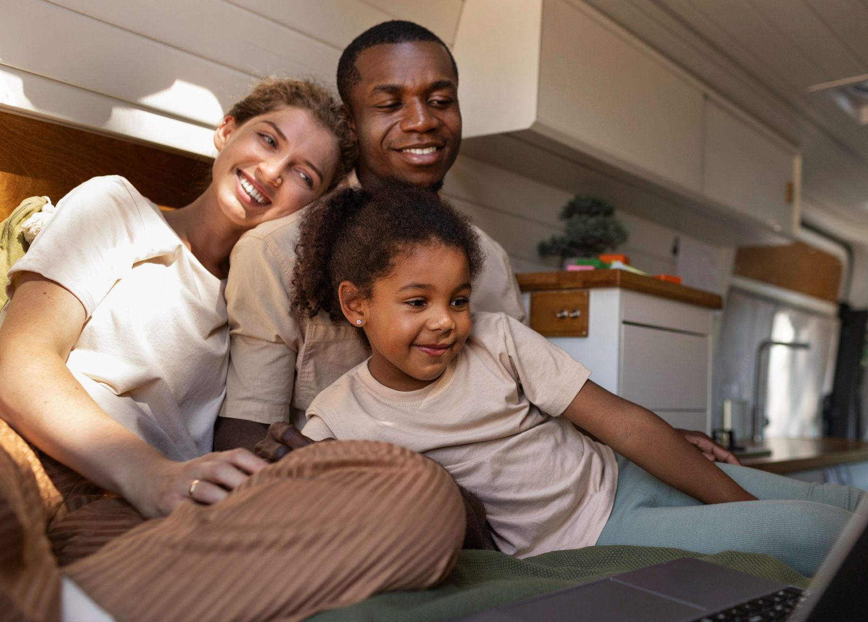 A family is sitting on the floor in front of a laptop computer.