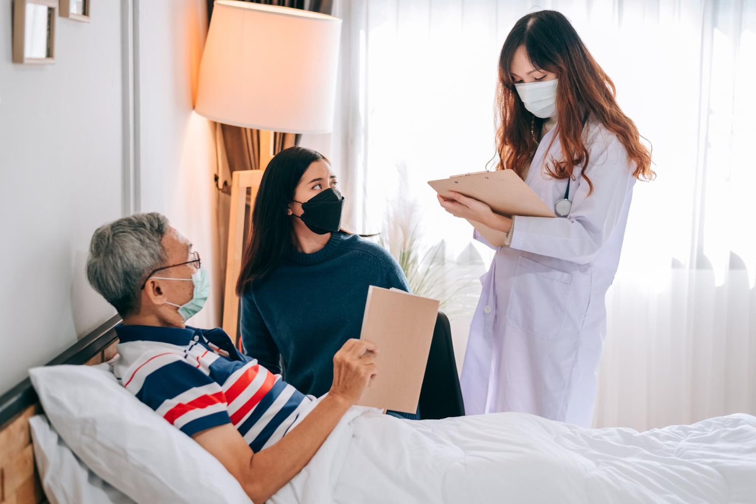 A nurse is talking to an elderly man in a hospital bed.