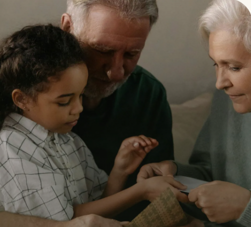 A man and a woman are sitting next to a little girl on a couch.