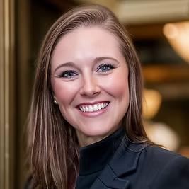 A woman in a black jacket is smiling for the camera.