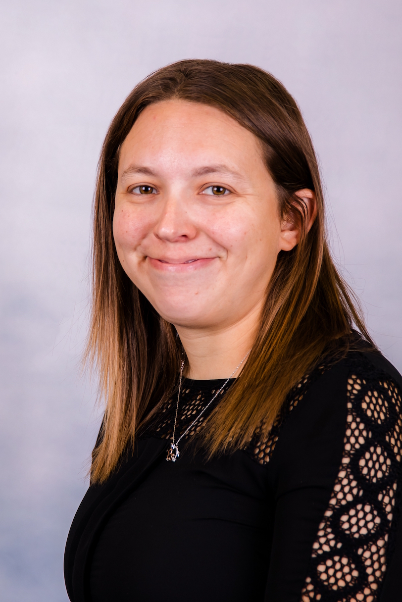 A woman in a black dress is smiling for the camera.