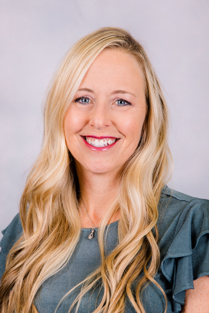 A woman with long blonde hair and blue eyes is smiling for the camera.