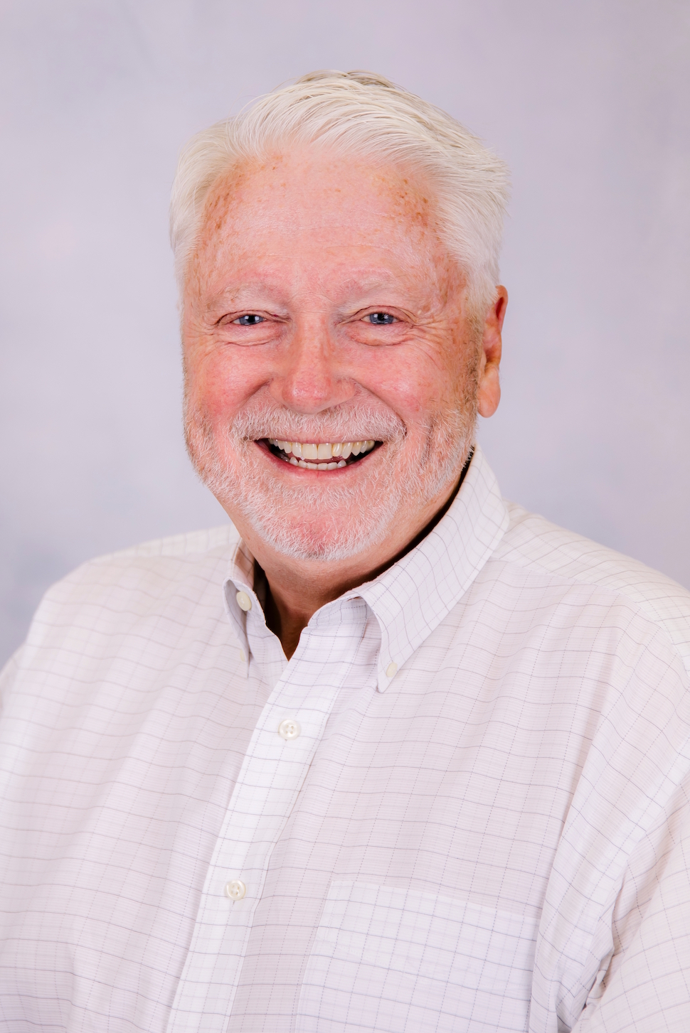 A man with gray hair and a beard is smiling for the camera.