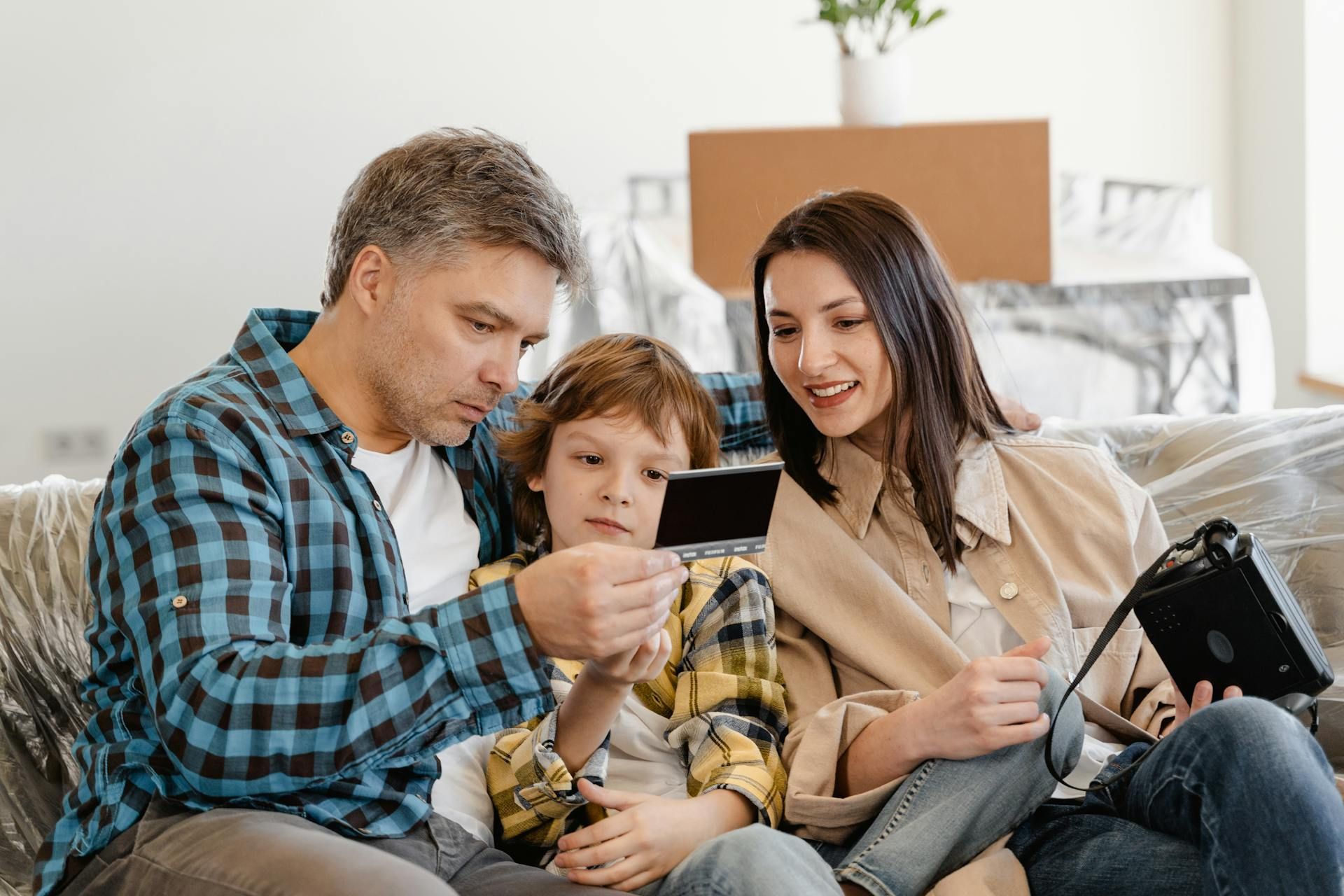 A family is sitting on a couch looking at a tablet.