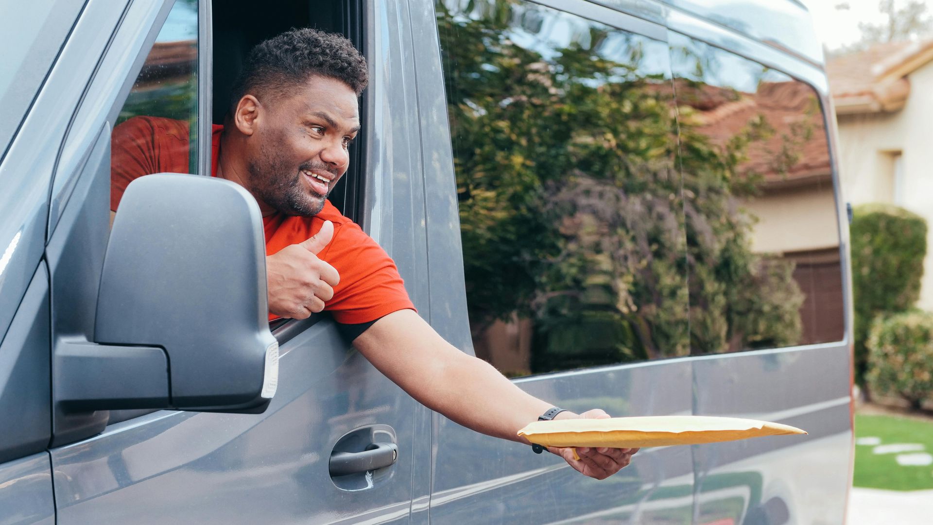 A delivery man is giving a thumbs up while holding a clipboard.