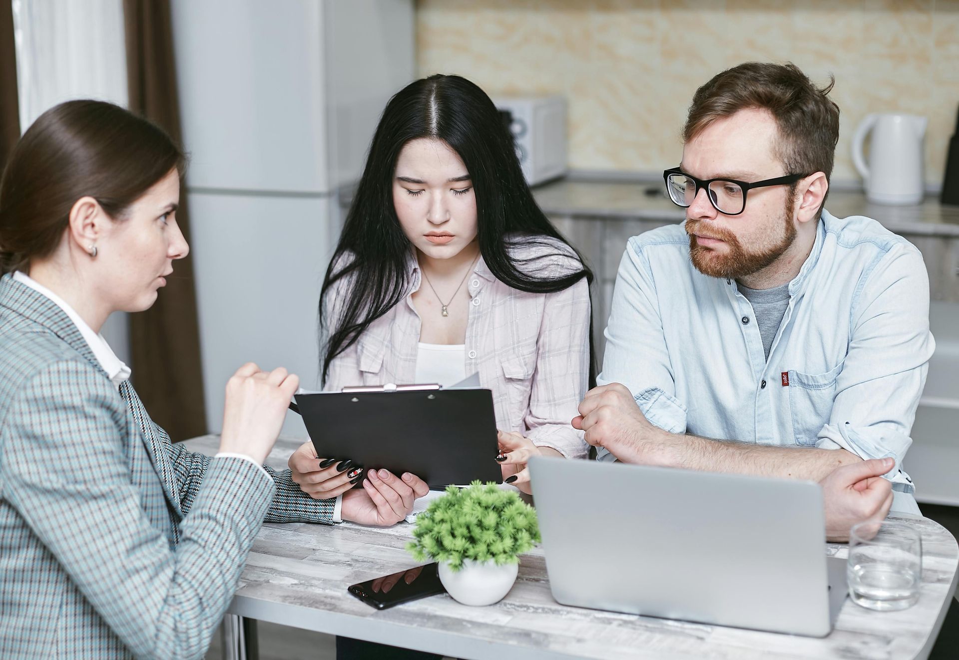 A man and a woman are sitting at a table with a laptop.