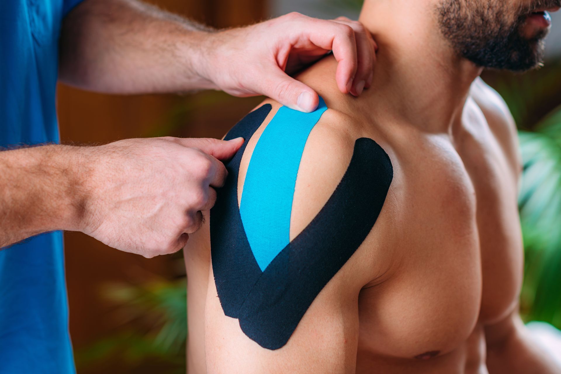 A man is getting kinesio tape on his shoulder.