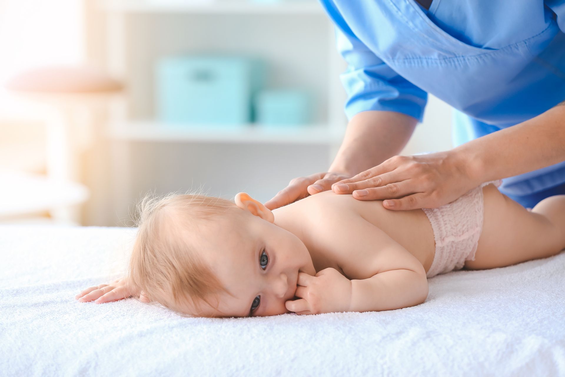 A woman is giving a baby a massage on a bed.