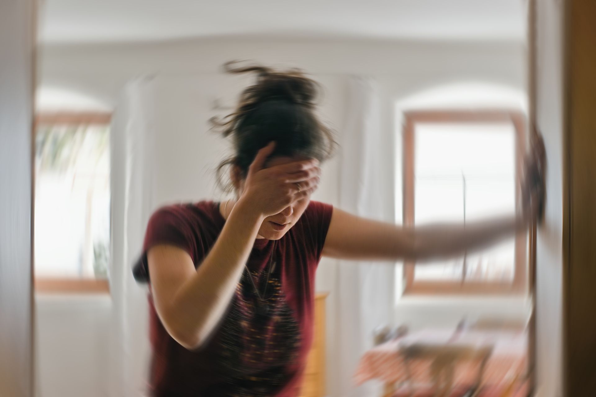 A woman is covering her face with her hand while standing in a doorway.