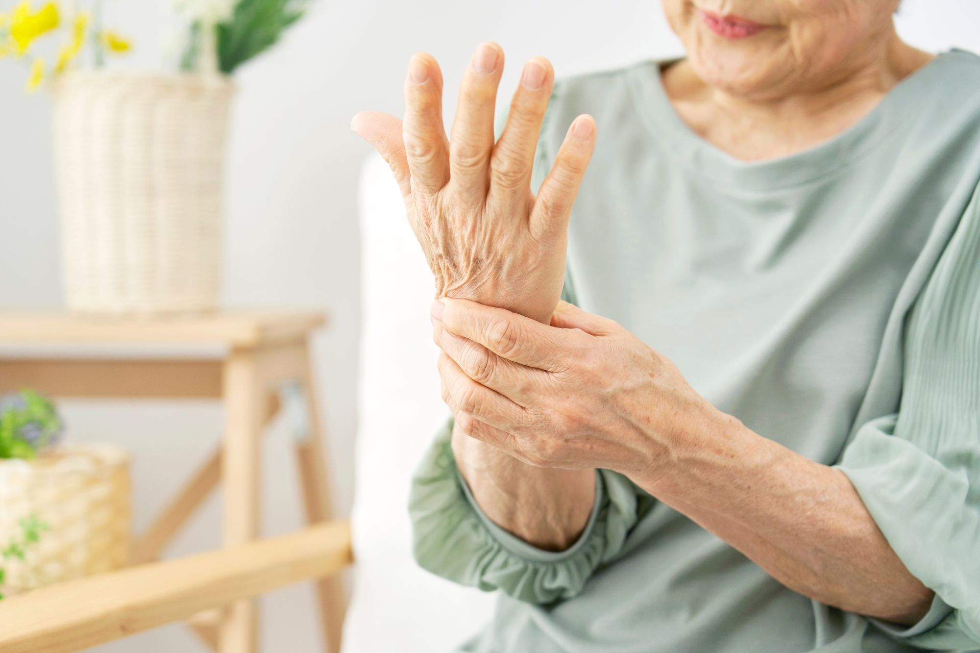 An elderly woman is holding her wrist in pain.