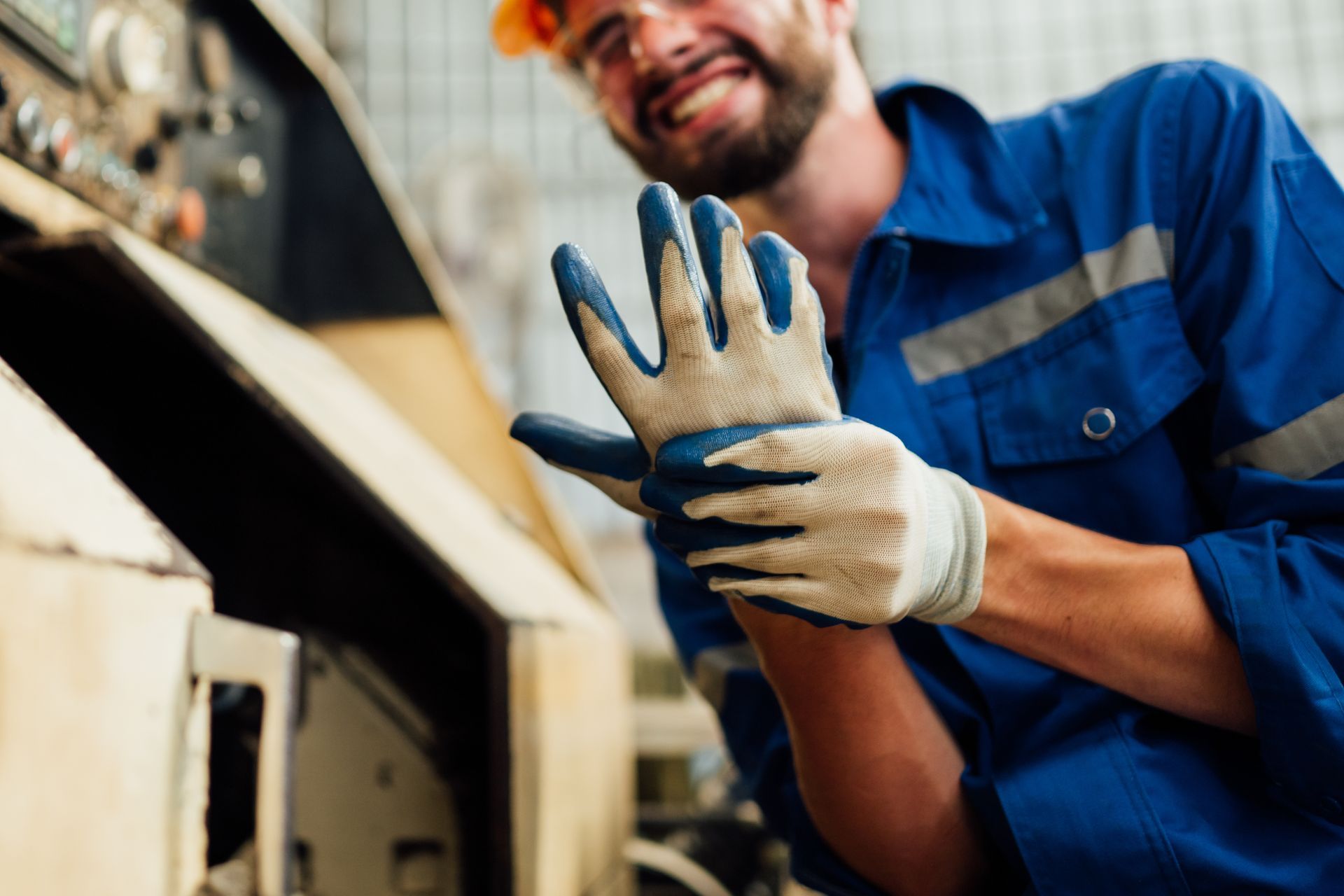 A man in a blue uniform is wearing gloves and a hard hat.