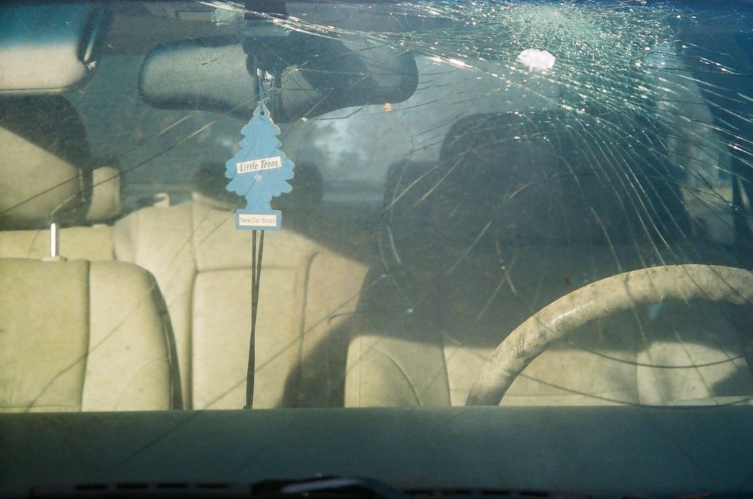 Interior of a car with a shattered windshield, air freshener hanging.