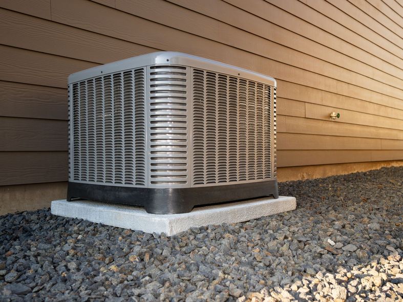 A large air conditioner is sitting outside of a house.