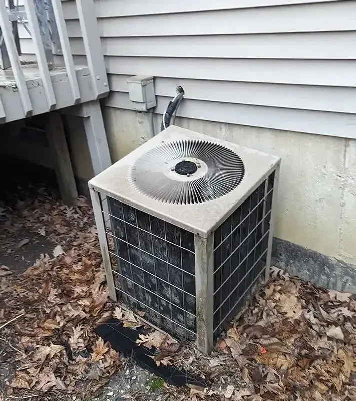 An air conditioner is sitting on the ground next to a house.