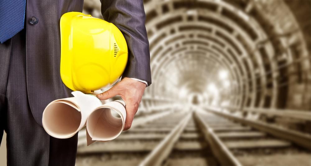 A Man in A Suit and Tie Is Holding a Hard Hat and Blueprints — Hillery Group in Bowen, QLD