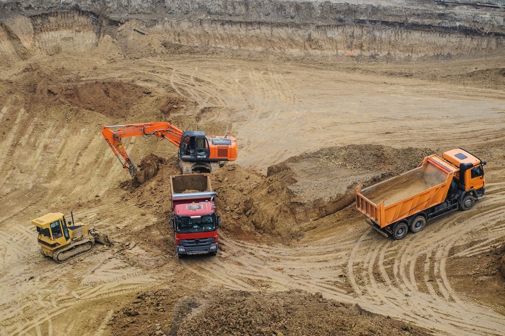 A Dump Truck Is Being Loaded with Dirt in A Construction Site — Hillery Group in Bowen, QLD