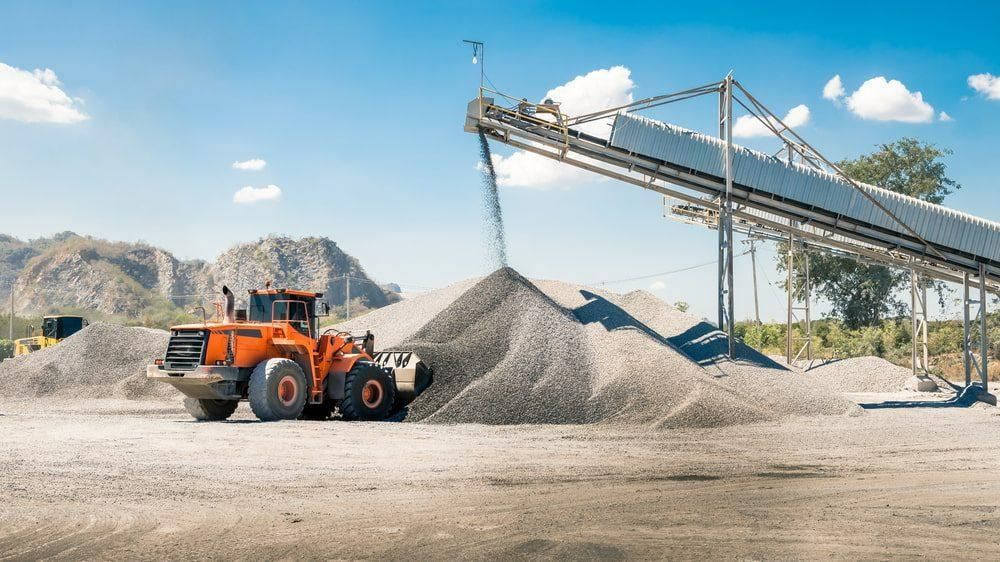 A Bulldozer Is Loading a Pile of Gravel Into a Conveyor Belt — Hillery Group in Bowen, QLD