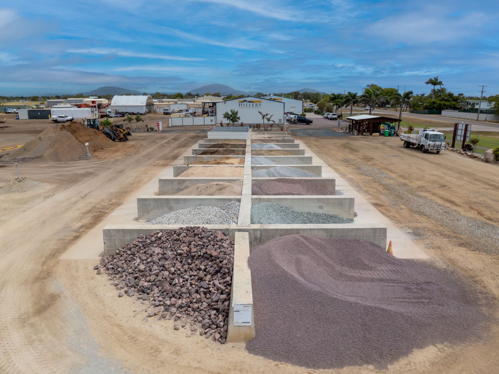 A Man Is Driving a Dump Truck in A Dirt Field — Hillery Group in Bowen, QLD