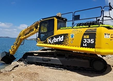 A yellow excavator is parked on the beach near the water.