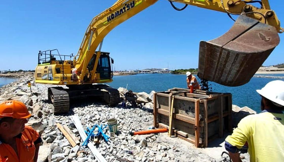 A Yellow Komatsu Excavator Is Digging a Hole in The Ground — Hillery Group in Bowen, QLD