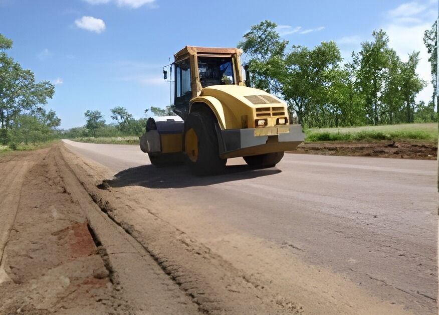 A Yellow Road Roller Is Driving Down a Dirt Road — Hillery Group in Bowen, QLD