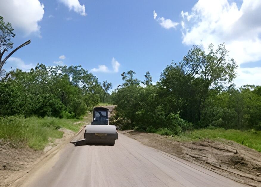 A Bulldozer Is Driving Down a Dirt Road — Hillery Group in Bowen, QLD