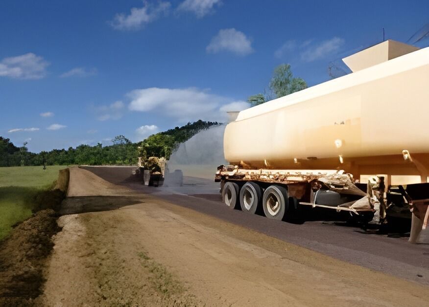 A Tanker Truck Is Spraying Water on A Dirt Road — Hillery Group in Bowen, QLD