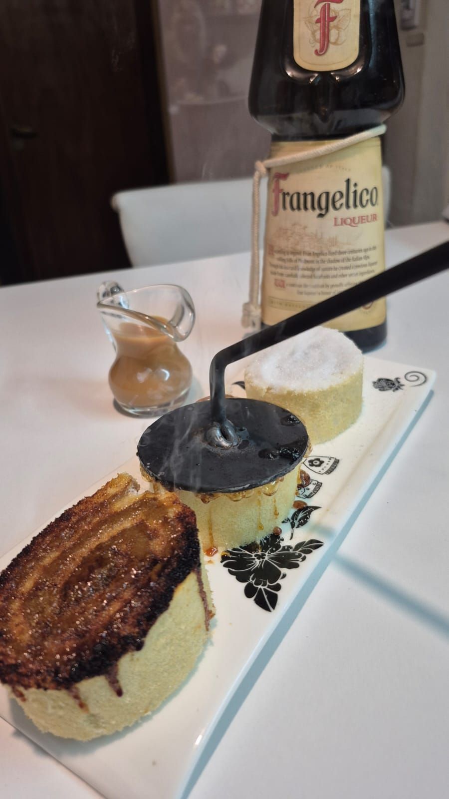 Tres postres individuales con una pequeña salsa y una botella de licor Frangelico.